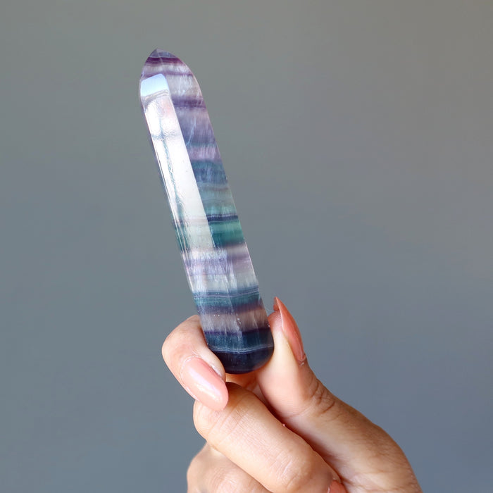 hand holding rainbow fluorite faceted massage wand