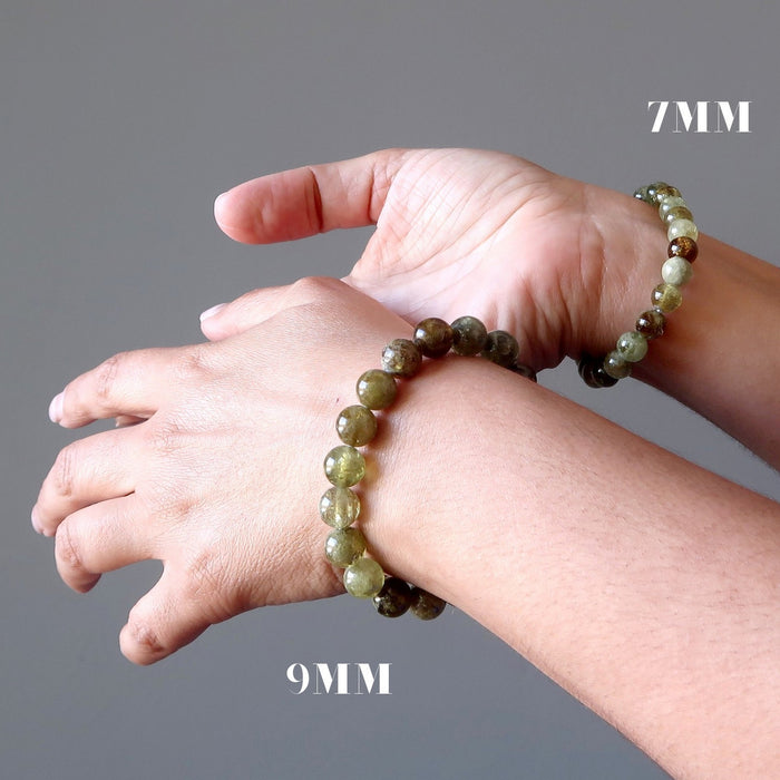 two hands posing wearing green garnet bracelets showing the difference between 7mm and 9mm beads