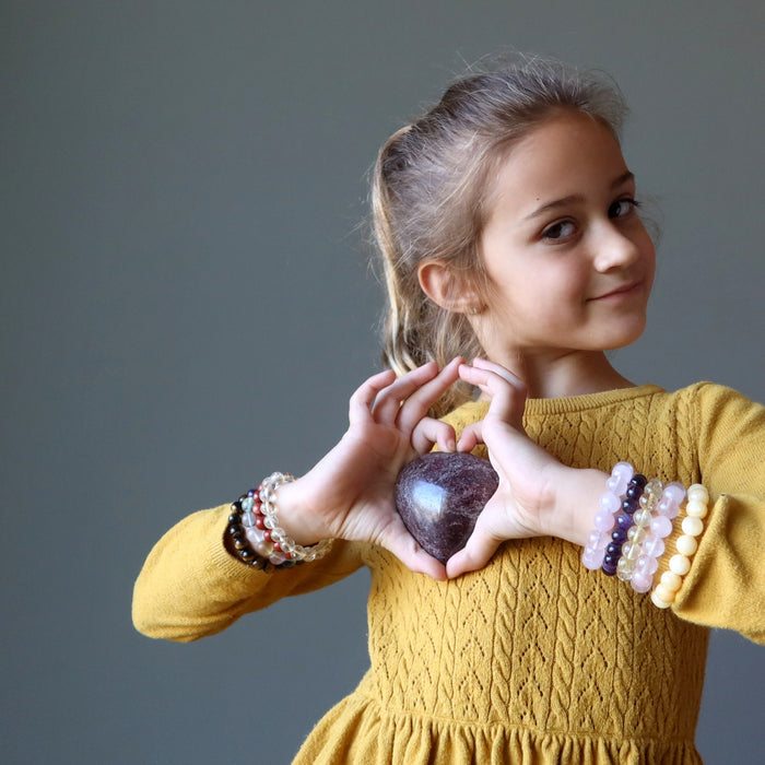 little girl holding a garnet heart to her chest