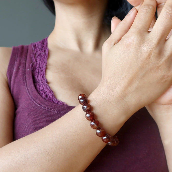 hand wearing hessonite garnet round beaded stretch bracelet