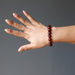 hand wearing hessonite garnet round beaded stretch bracelet