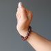 fisted hand wearing hessonite garnet round beaded stretch bracelet