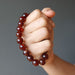fist holding hessonite garnet round beaded stretch bracelet