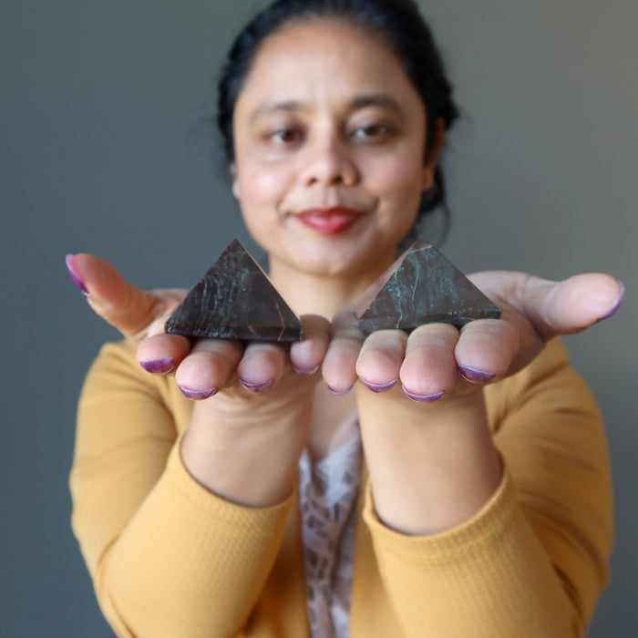 woman holding two red garnet pyramids