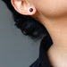 ear wearing dark red garnet stud earrings