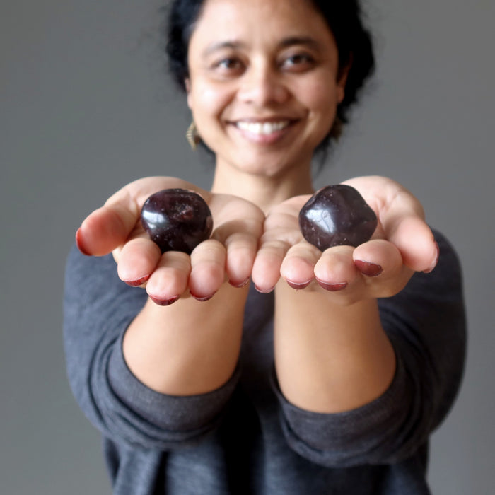 sheila of satin crystals holding garnet tumbled stones in each palm