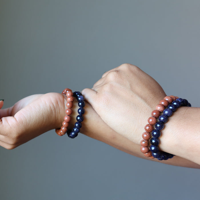 female hands wearing goldstone bracelet sets