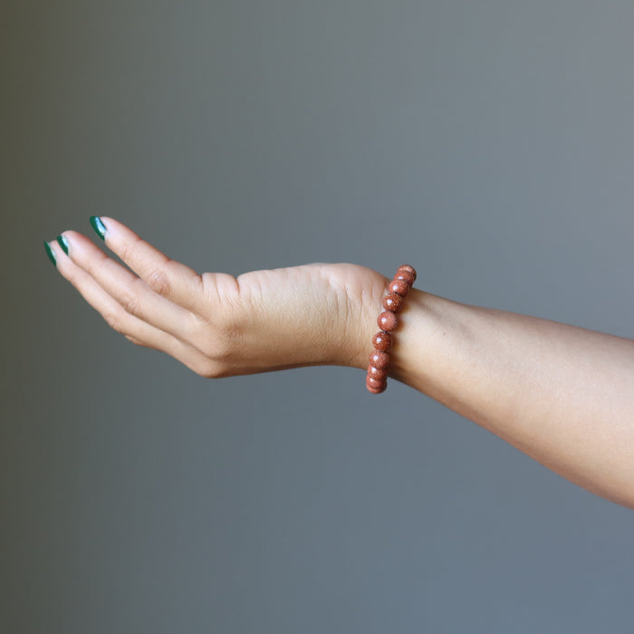female hand wearing brown goldstone bracelet