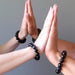 two sets of hands together all wearing hawks eye bracelets