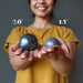 female holding hematite spheres in each hand showing size difference between 2.0" and 1.5"