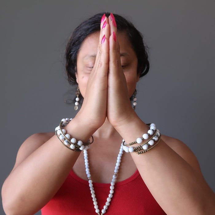 sheila of satin crystals with hands in prayer wearing howlite coil bracelets on both wrists