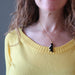 a model wearing black onyx and white howlite penguin pendant on 14 karat gold necklace chain