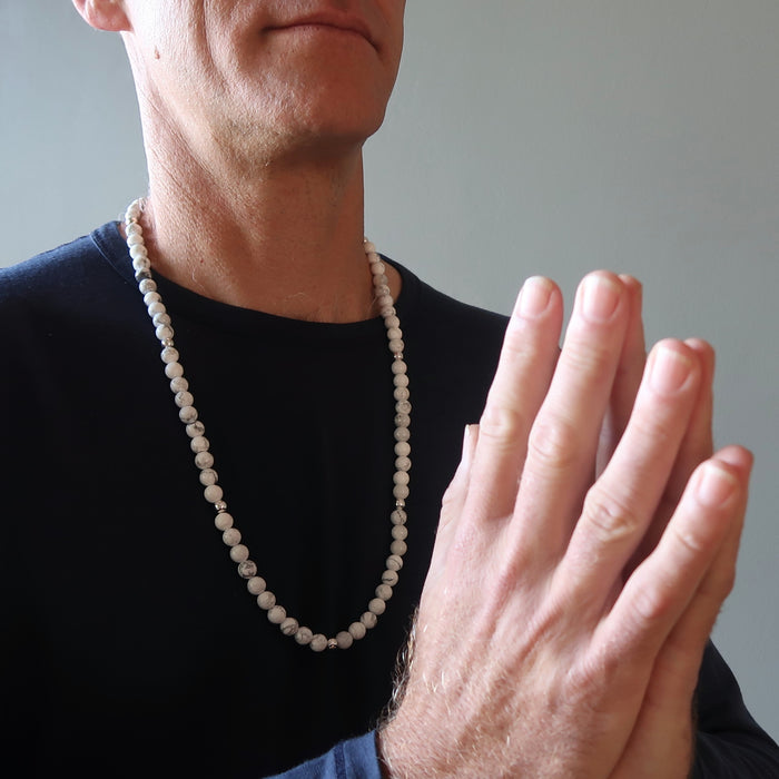 male model wearing long howlite beaded necklace with folded hands 