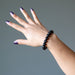 female hand raised up modeling hypersthene bracelet