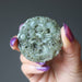 hand holding green jadeite amulet carved with dragon and money coins
