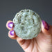 hand holding green jadeite amulet carved with dragon and money coins