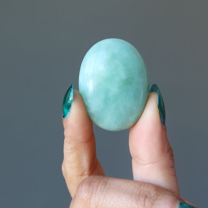 hand holding up a green jade oval