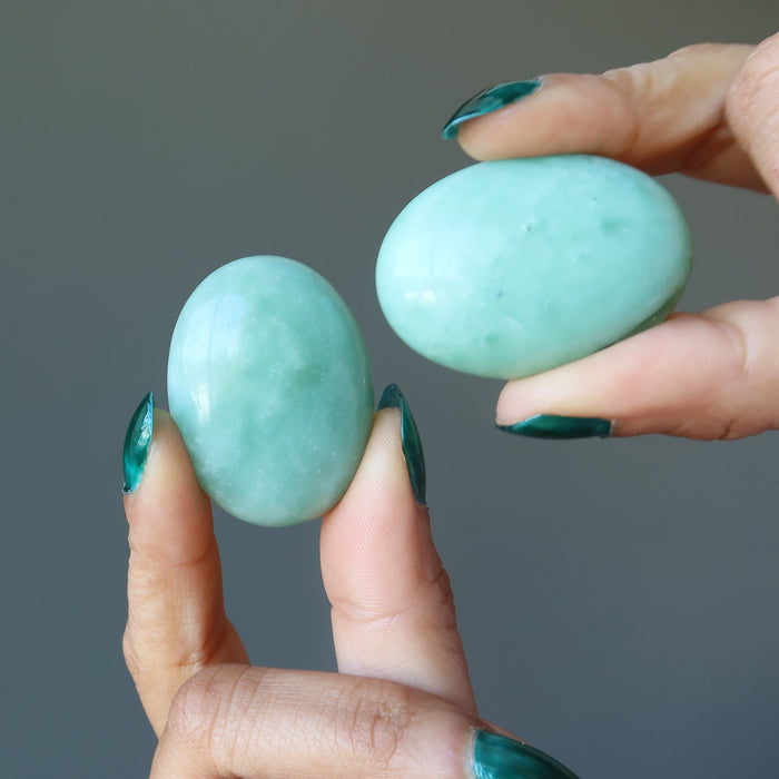 hands holding pair of green jade oval cabochons