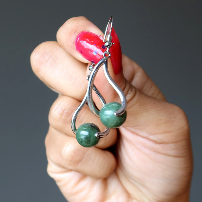woman holding jade earrings