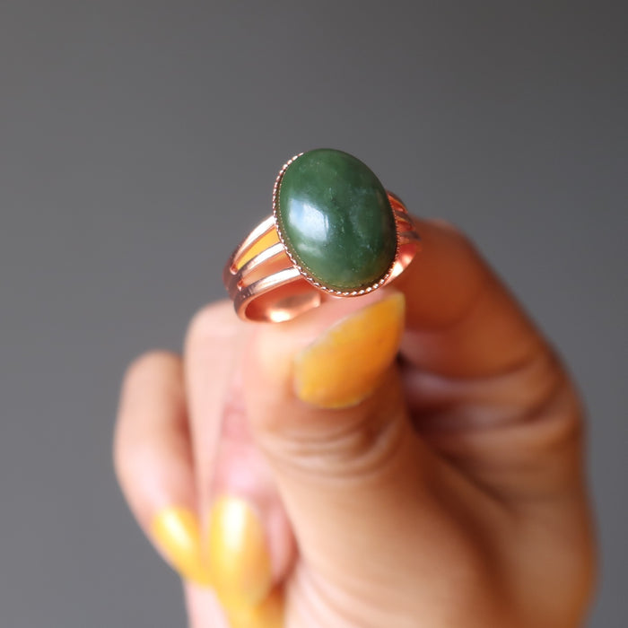 hand holding green jade oval in copper adjustable ring