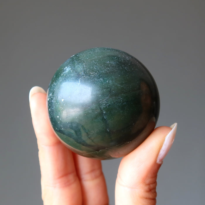 hand holding dark green nephrite jade sphere