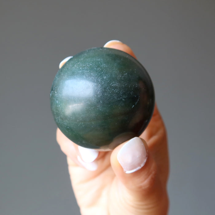 hand holding dark green nephrite jade sphere