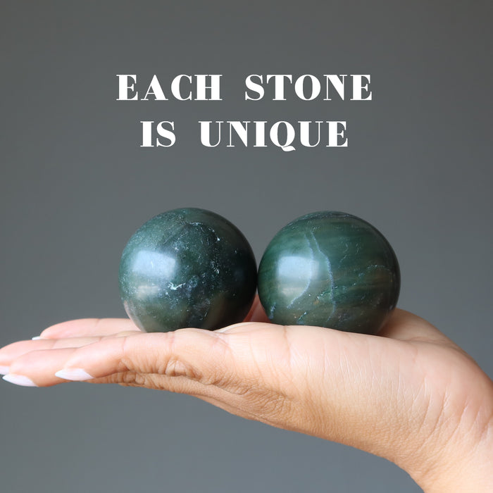 hand holding two dark green nephrite jade spheres