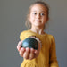 little girl holding dark green nephrite jade sphere