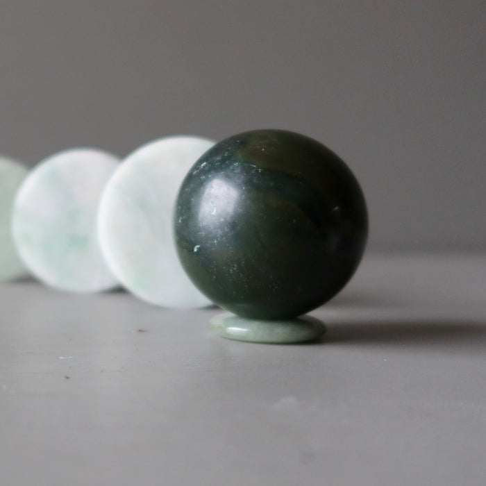 jade sphere on jade donut stand in front of jade circle slabs