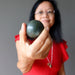 woman holding dark green nephrite jade sphere