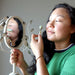 female model using a jade roller on her face in a mirror