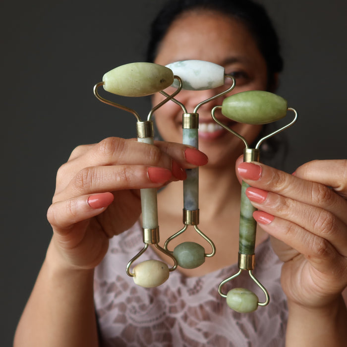 female holding three jade facial rollers