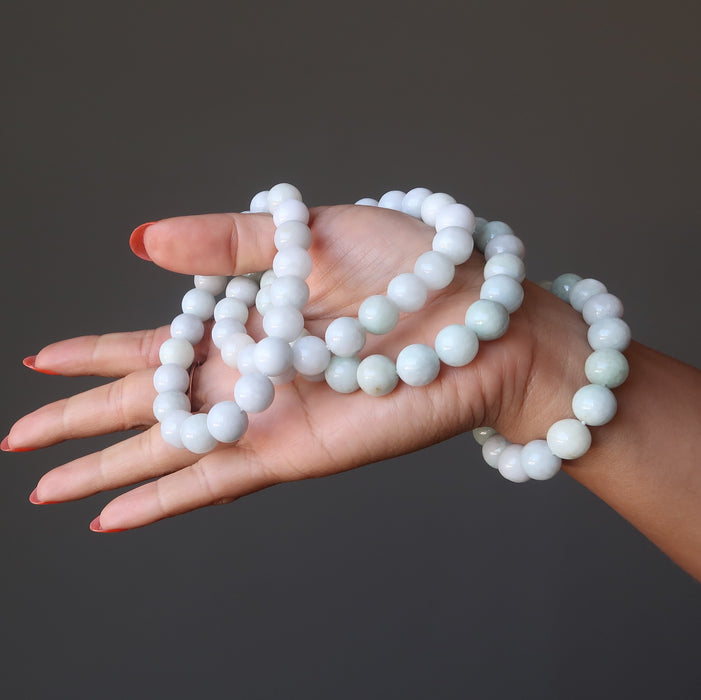 hand holding and wearing white jade round beaded stretch bracelets