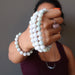 woman holding 3 white jade round beaded stretch bracelets