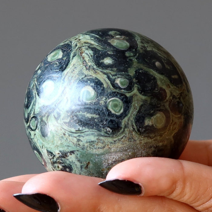 green kambaba jasper sphere in hand