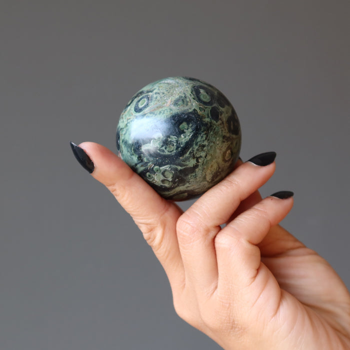 green kambaba jasper sphere in hand