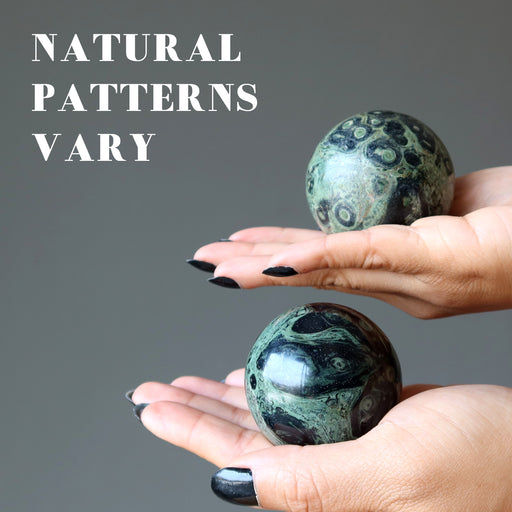 green kambaba jasper spheres in palms of hand showing natural patterns vary