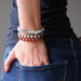 lucia of satin crystals with hands in back jean pockets, wearing set of 3 sesame, red and dalmatian jasper stretch bracelets on each hand.
