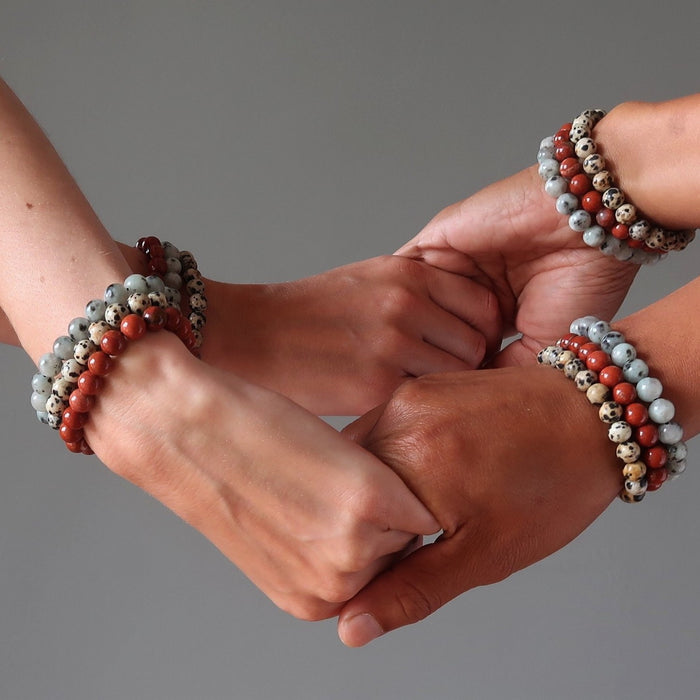 4 hands holding each other all wearing stackable jasper medley bracelets
