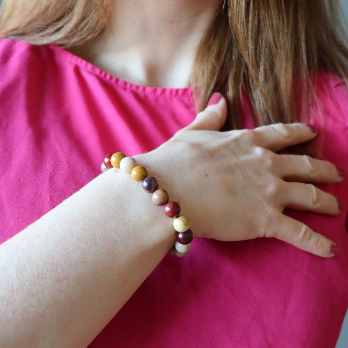 holly of satin crystals with hand on heart wearing multi colored mookaite jasper round beaded stretch bracelet