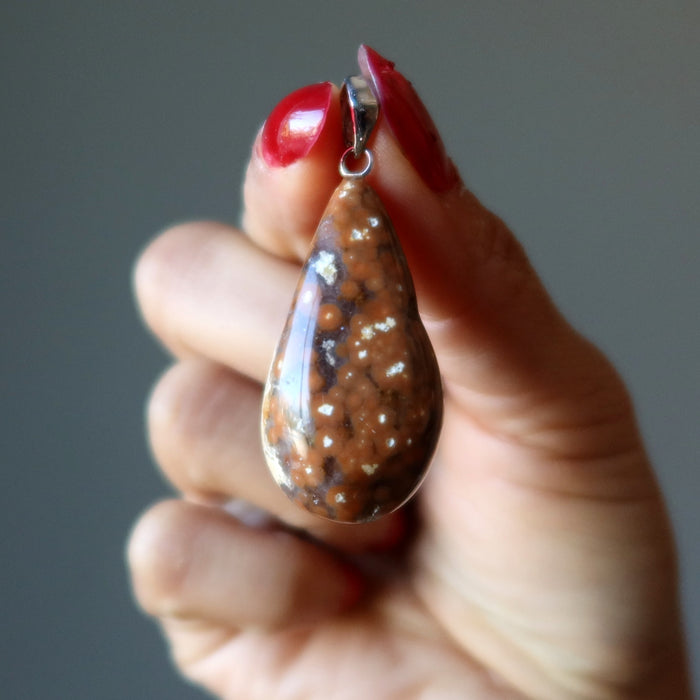 hand holding brown ocean jasper pendant