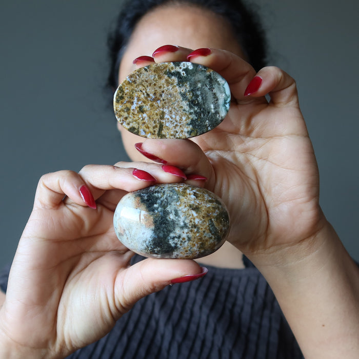 female holding two ocean jasper oval stones
