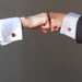 man and woman's hands fist bumping both wearing red jasper cufflinks on their french cuffs