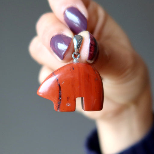 hand holding red jasper bear pendant