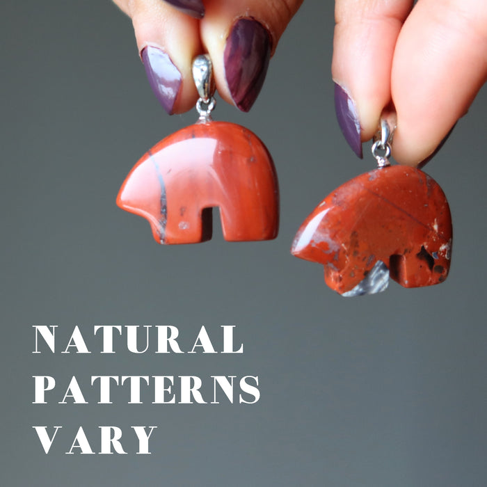hand holding red jasper bear pendants to show nautral patterns vary