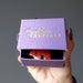 hand holding red jasper bear pendant in purple satin crystals gift box