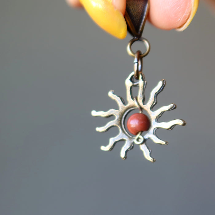 hand holding red jasper sun pendant showing the back