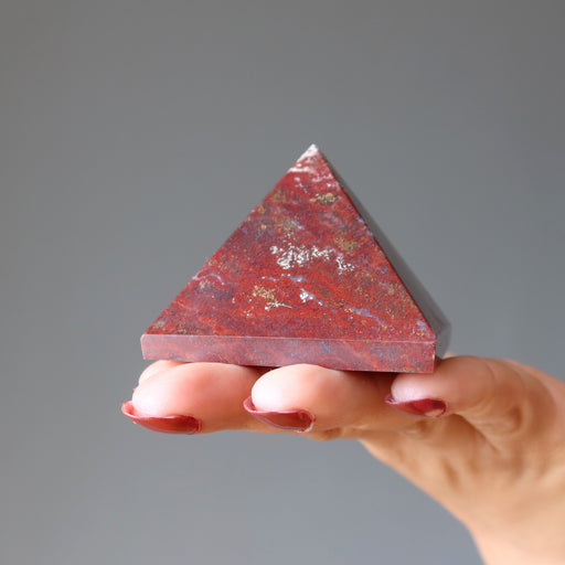 hand holding red jasper pyramid