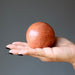 hand holding a red jasper crystal ball
