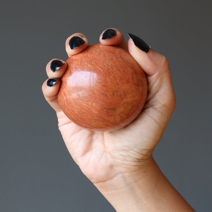 hand holding a red jasper crystal ball